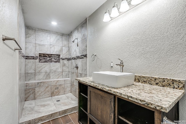 bathroom featuring a tile shower and vanity