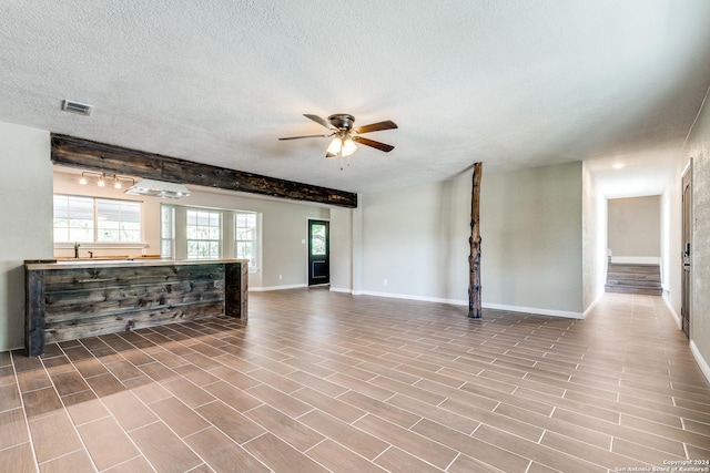 unfurnished living room featuring ceiling fan and a textured ceiling