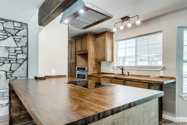 kitchen with sink, oven, wood counters, black electric cooktop, and extractor fan