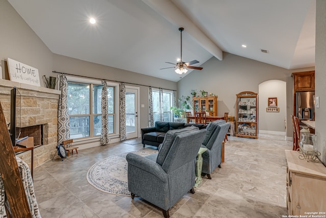 living room featuring light tile patterned floors, ceiling fan, beamed ceiling, a stone fireplace, and high vaulted ceiling