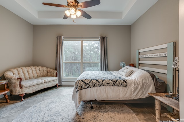 bedroom with tile patterned floors, a raised ceiling, and ceiling fan