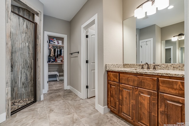 bathroom with vanity, a tile shower, and tile patterned flooring