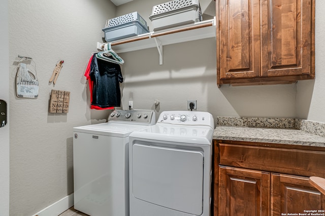 clothes washing area with washer and dryer and cabinets