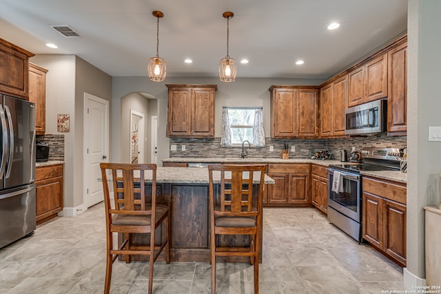 kitchen with appliances with stainless steel finishes, light tile patterned floors, decorative backsplash, and a kitchen island