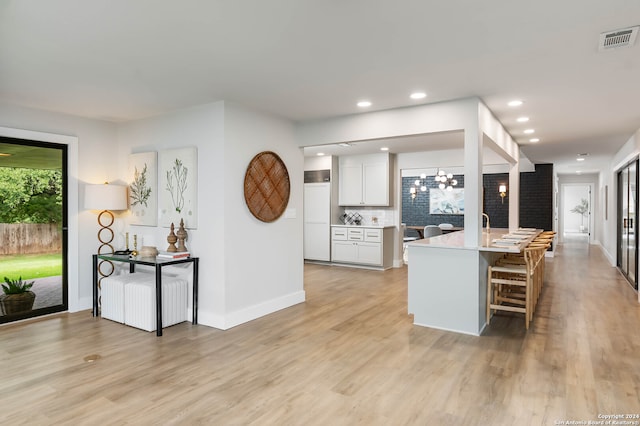 kitchen with light hardwood / wood-style floors, white cabinetry, a kitchen bar, and backsplash