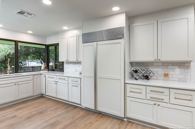 kitchen with light hardwood / wood-style floors, white cabinetry, paneled refrigerator, and decorative backsplash