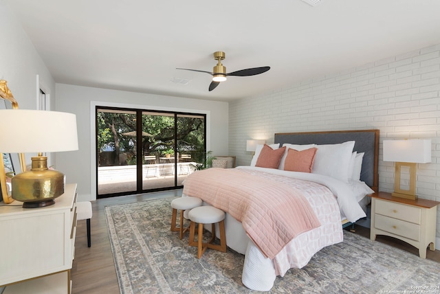 bedroom with brick wall, access to exterior, ceiling fan, and hardwood / wood-style floors