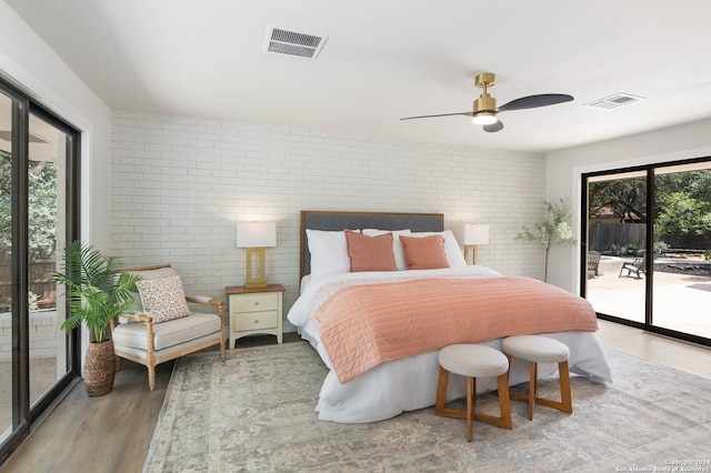 bedroom featuring wood-type flooring, access to outside, brick wall, and ceiling fan