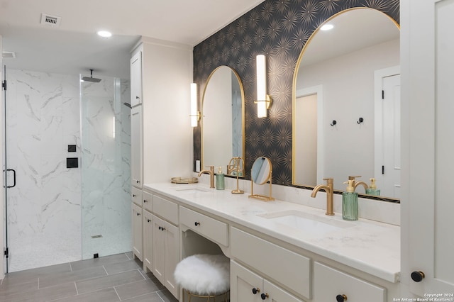 bathroom with a shower with shower door, double vanity, and tile patterned floors