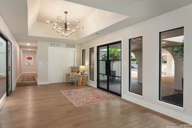 interior space featuring hardwood / wood-style flooring, a raised ceiling, and an inviting chandelier