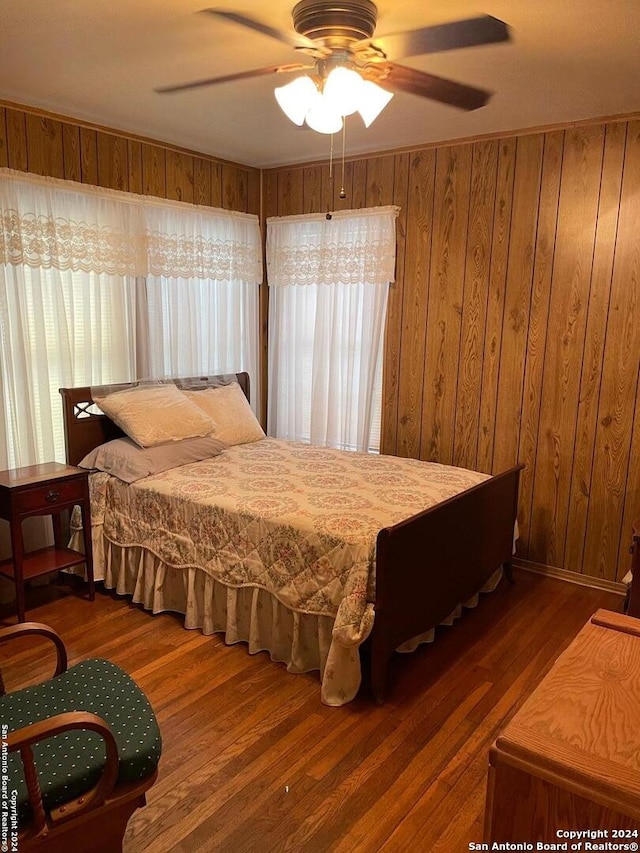 bedroom featuring hardwood / wood-style floors, ceiling fan, and wood walls