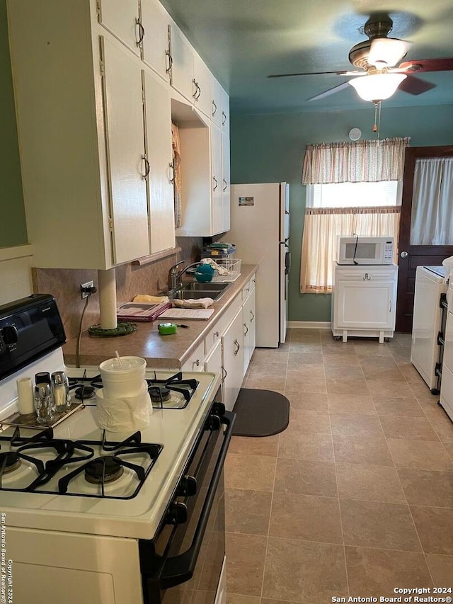 kitchen featuring sink, white cabinets, and white appliances