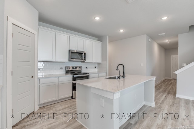 kitchen with white cabinetry, sink, a kitchen island with sink, stainless steel appliances, and light stone countertops