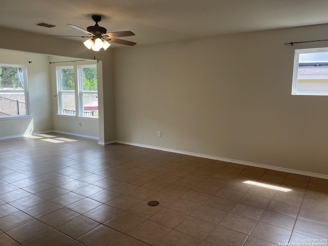 tiled empty room featuring ceiling fan and a healthy amount of sunlight