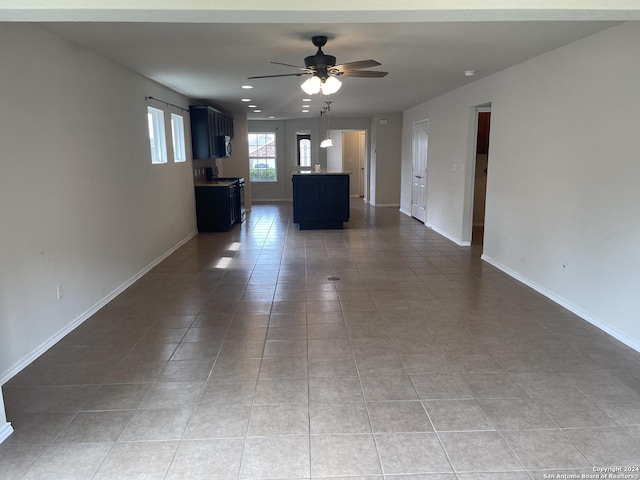 unfurnished living room featuring ceiling fan and tile patterned flooring