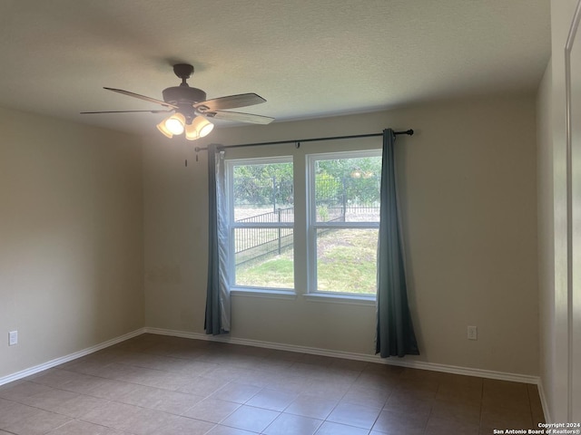 empty room with light tile patterned floors, a textured ceiling, and ceiling fan