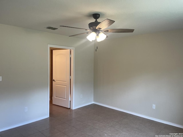 spare room featuring dark tile patterned flooring and ceiling fan