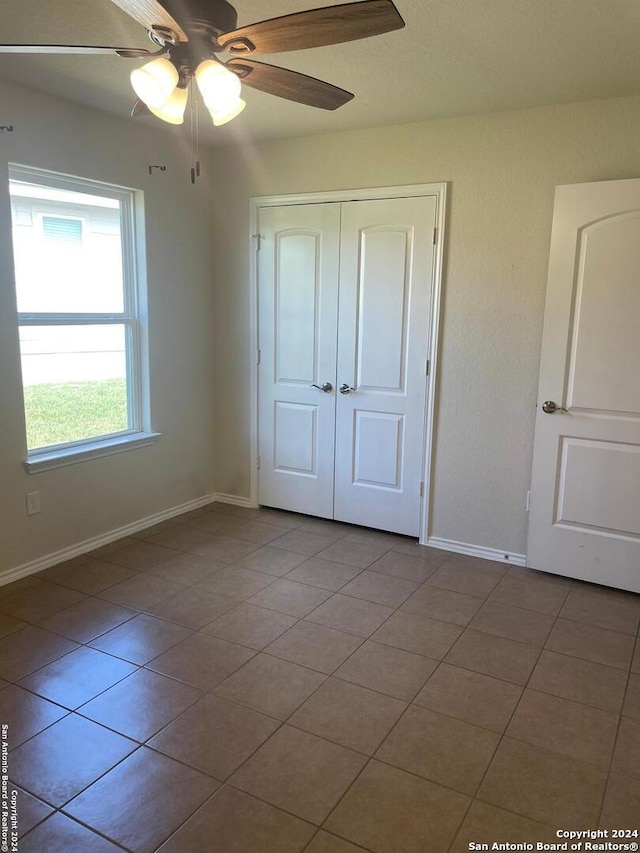 unfurnished bedroom with light tile patterned floors, a closet, and ceiling fan