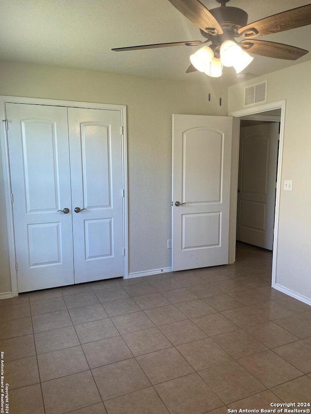 unfurnished bedroom with ceiling fan, light tile patterned floors, and a closet