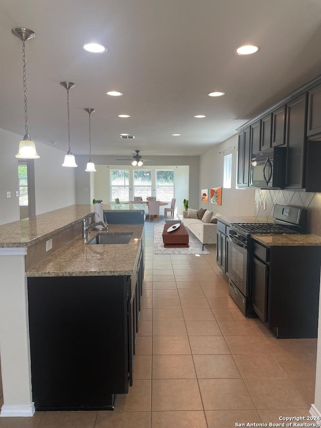 kitchen with light stone countertops, sink, tasteful backsplash, decorative light fixtures, and black appliances