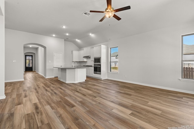 unfurnished living room featuring vaulted ceiling, sink, ceiling fan, and light hardwood / wood-style flooring