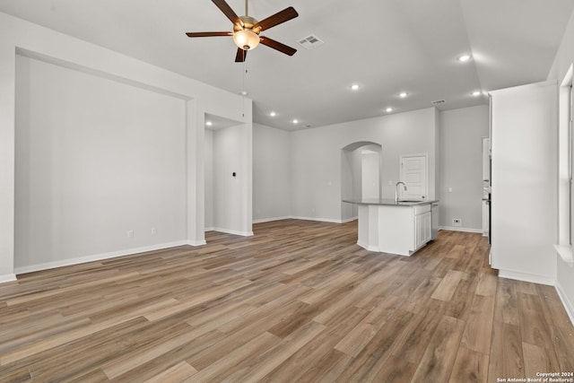 unfurnished living room featuring sink, ceiling fan, and light hardwood / wood-style flooring