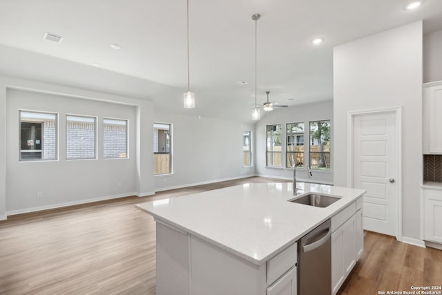 kitchen with pendant lighting, sink, dishwasher, white cabinetry, and a center island with sink