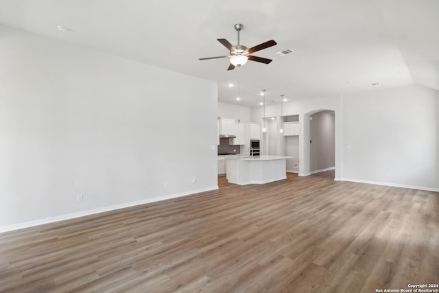 unfurnished living room with sink, ceiling fan, and light wood-type flooring