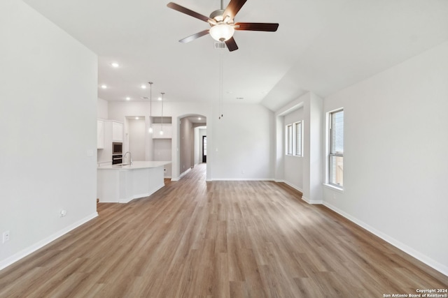 unfurnished living room with sink, ceiling fan, and light wood-type flooring