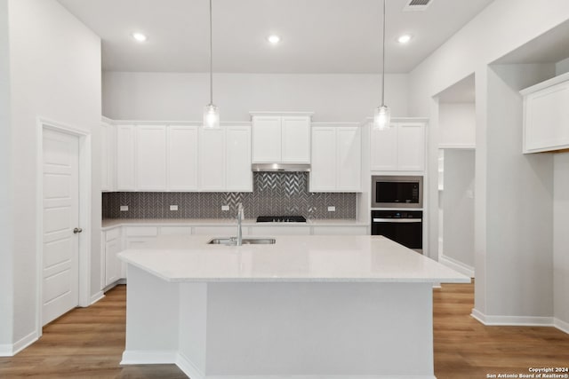 kitchen featuring decorative light fixtures, a kitchen island with sink, and black appliances