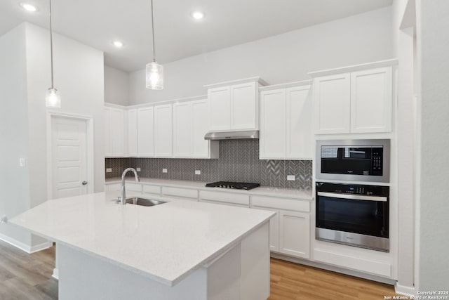 kitchen featuring appliances with stainless steel finishes, sink, pendant lighting, and white cabinets