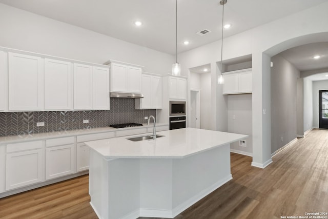 kitchen featuring sink, a kitchen island with sink, hanging light fixtures, black appliances, and white cabinets