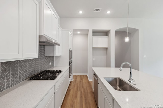 kitchen with pendant lighting, sink, white cabinets, stainless steel appliances, and light stone countertops