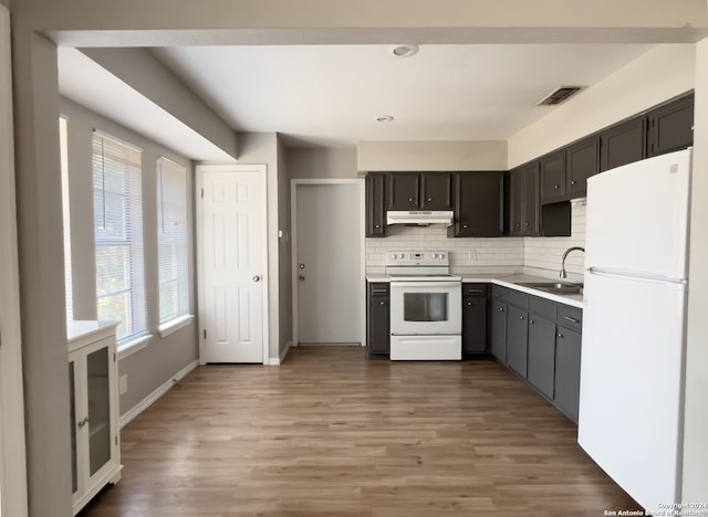 kitchen featuring backsplash, sink, white appliances, and hardwood / wood-style floors