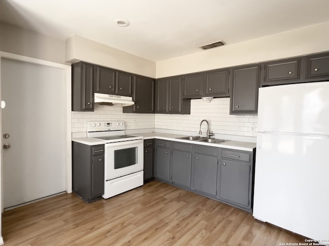 kitchen featuring sink, light hardwood / wood-style flooring, tasteful backsplash, and white appliances