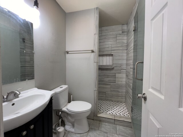 bathroom featuring vanity, an enclosed shower, tile patterned flooring, and toilet