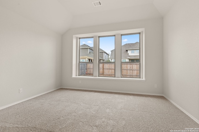 carpeted empty room with lofted ceiling