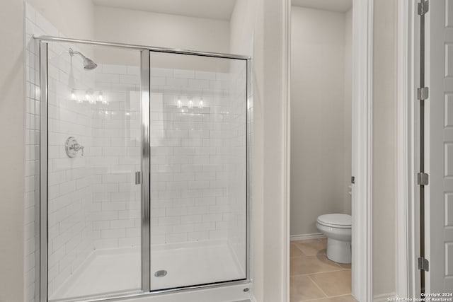 bathroom featuring toilet, tile patterned floors, and a shower with shower door