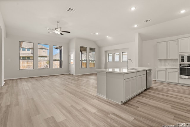 kitchen with sink, light wood-type flooring, vaulted ceiling, and a healthy amount of sunlight