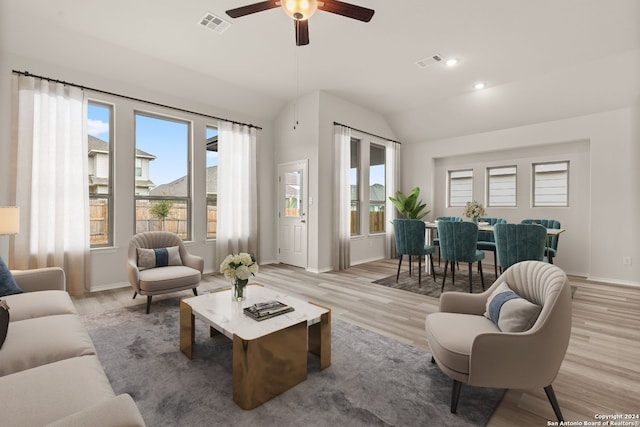 living room with light hardwood / wood-style floors, ceiling fan, and vaulted ceiling