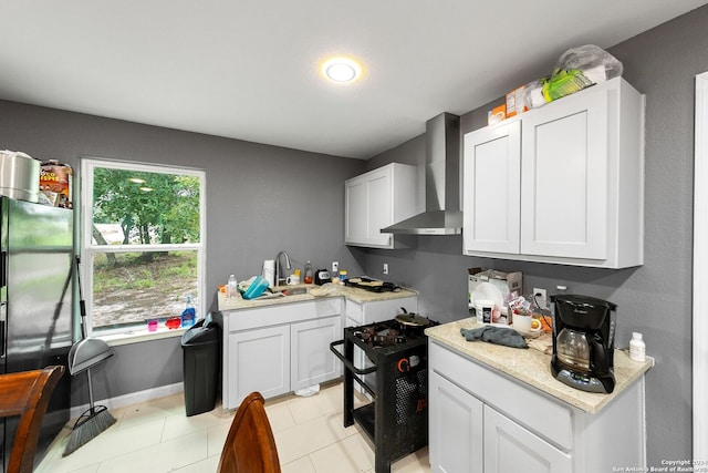 kitchen with wall chimney exhaust hood, sink, white cabinets, light stone countertops, and stove