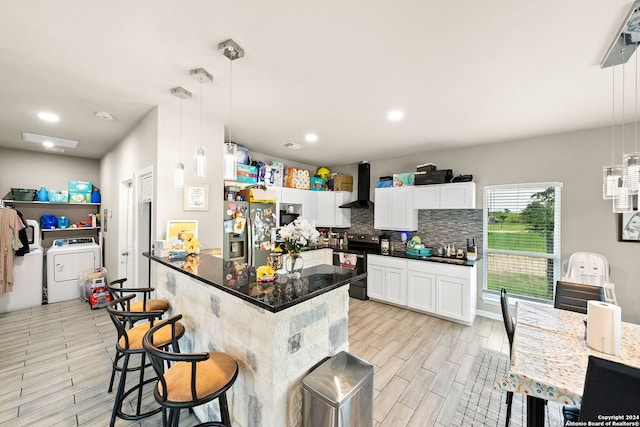 kitchen featuring black / electric stove, white cabinetry, hanging light fixtures, stainless steel refrigerator with ice dispenser, and wall chimney exhaust hood