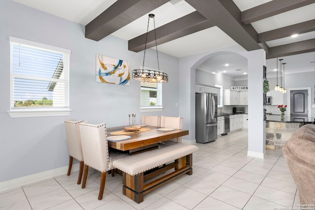 tiled dining space with sink, beamed ceiling, and crown molding