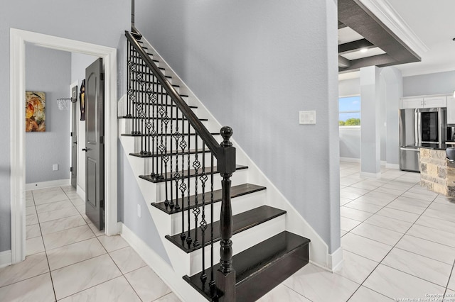 staircase with ornamental molding and tile patterned flooring