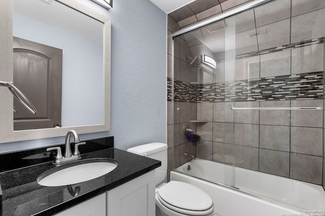 full bath featuring toilet, a textured wall, vanity, and combined bath / shower with glass door