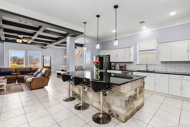 kitchen featuring a kitchen island, beamed ceiling, hanging light fixtures, stainless steel refrigerator, and coffered ceiling