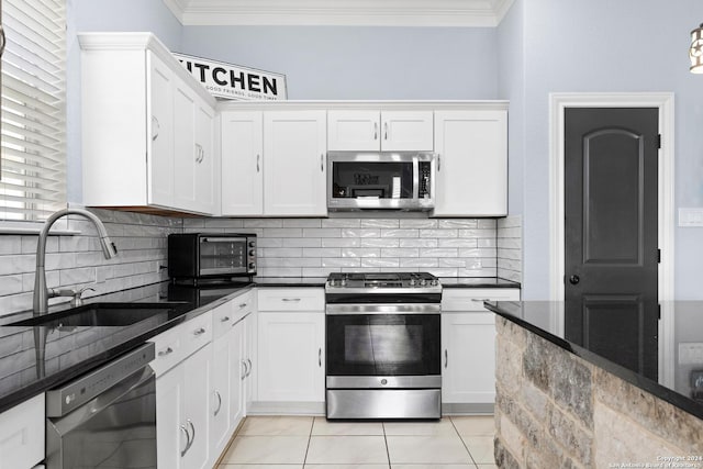 kitchen featuring white cabinetry, stainless steel appliances, dark stone counters, tasteful backsplash, and sink