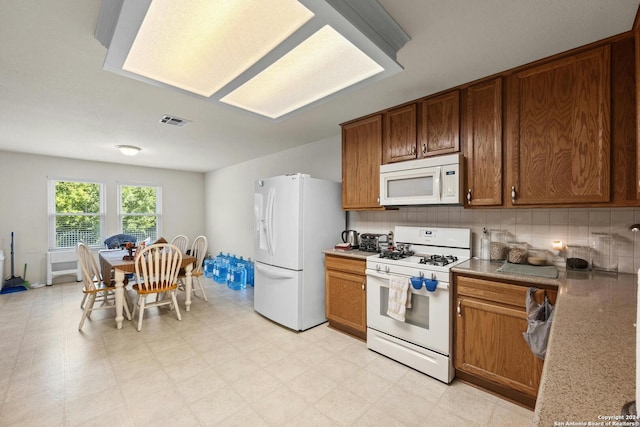 kitchen featuring light tile patterned floors, backsplash, and white appliances