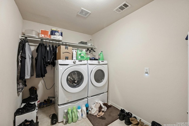 laundry room with washer and clothes dryer, light tile patterned floors, and a textured ceiling