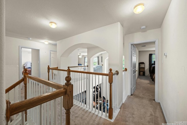 corridor featuring light carpet and a textured ceiling